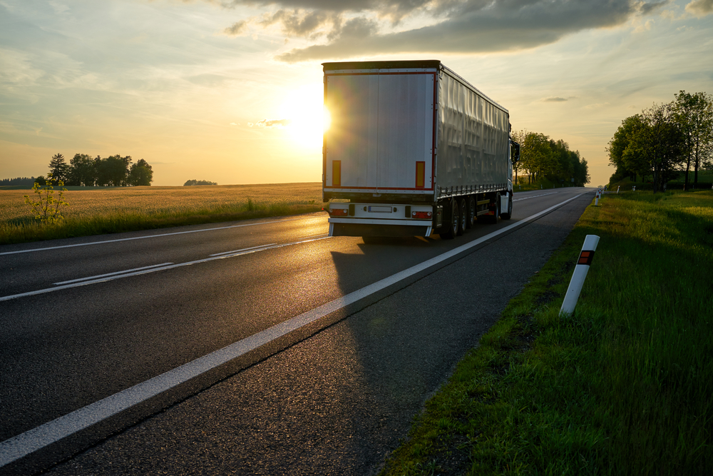 Truck,departing,towards,the,horizon,on,an,asphalt,road,in