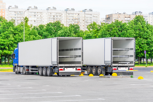 Two,trucks,in,a,parking,lot,with,an,empty,container