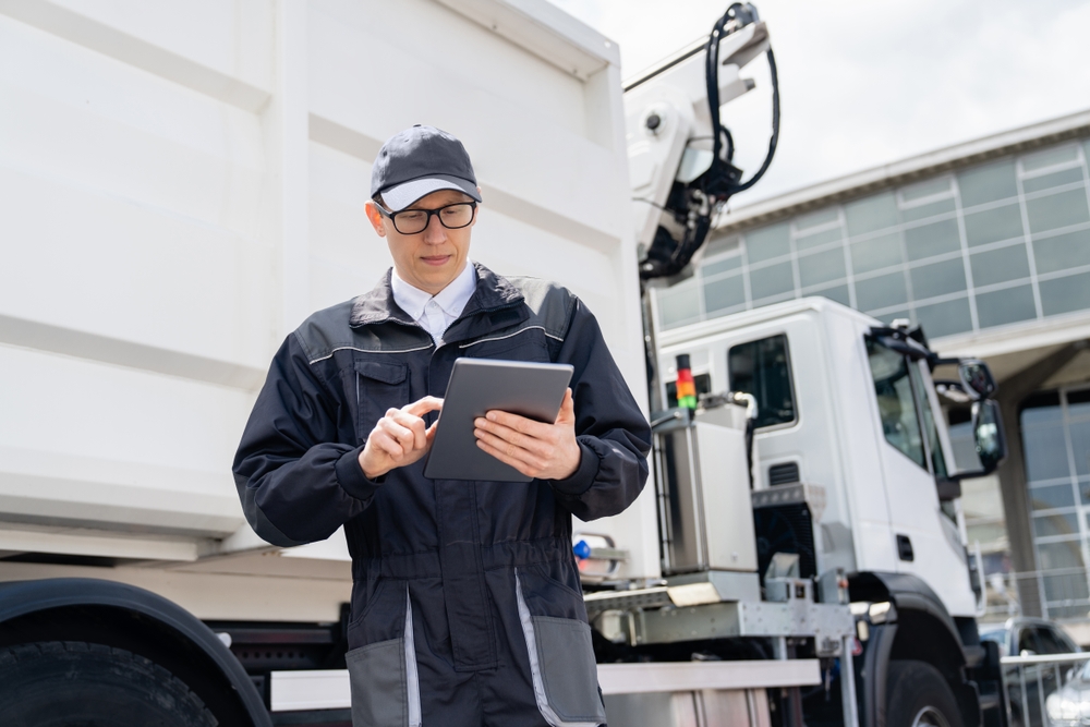 Manager,with,a,digital,tablet,next,to,garbage,truck.
