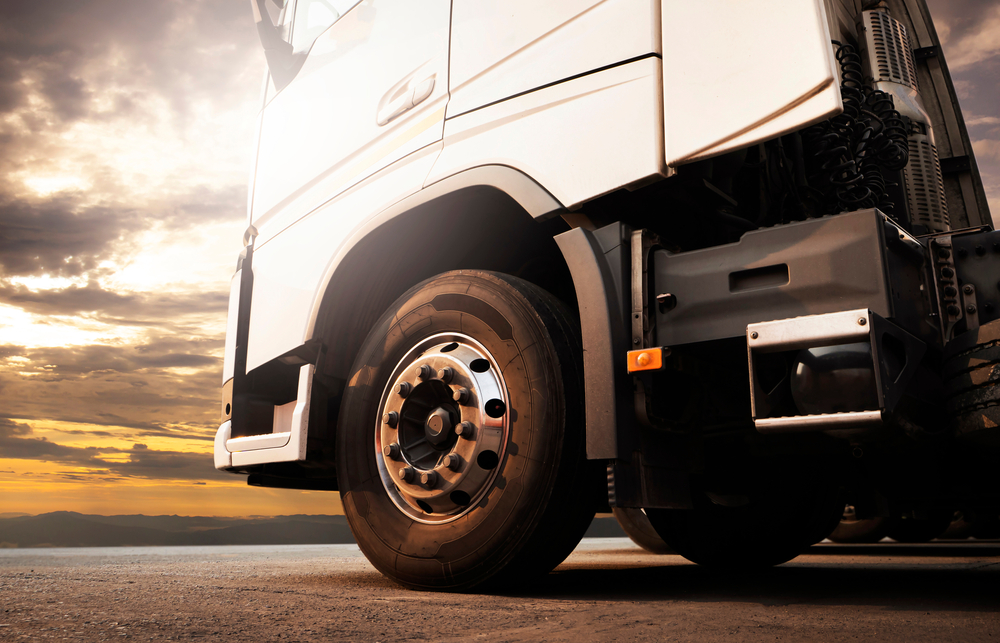 Front,of,semi,truck,parked,at,sunset,sky.,truck,wheels.industry